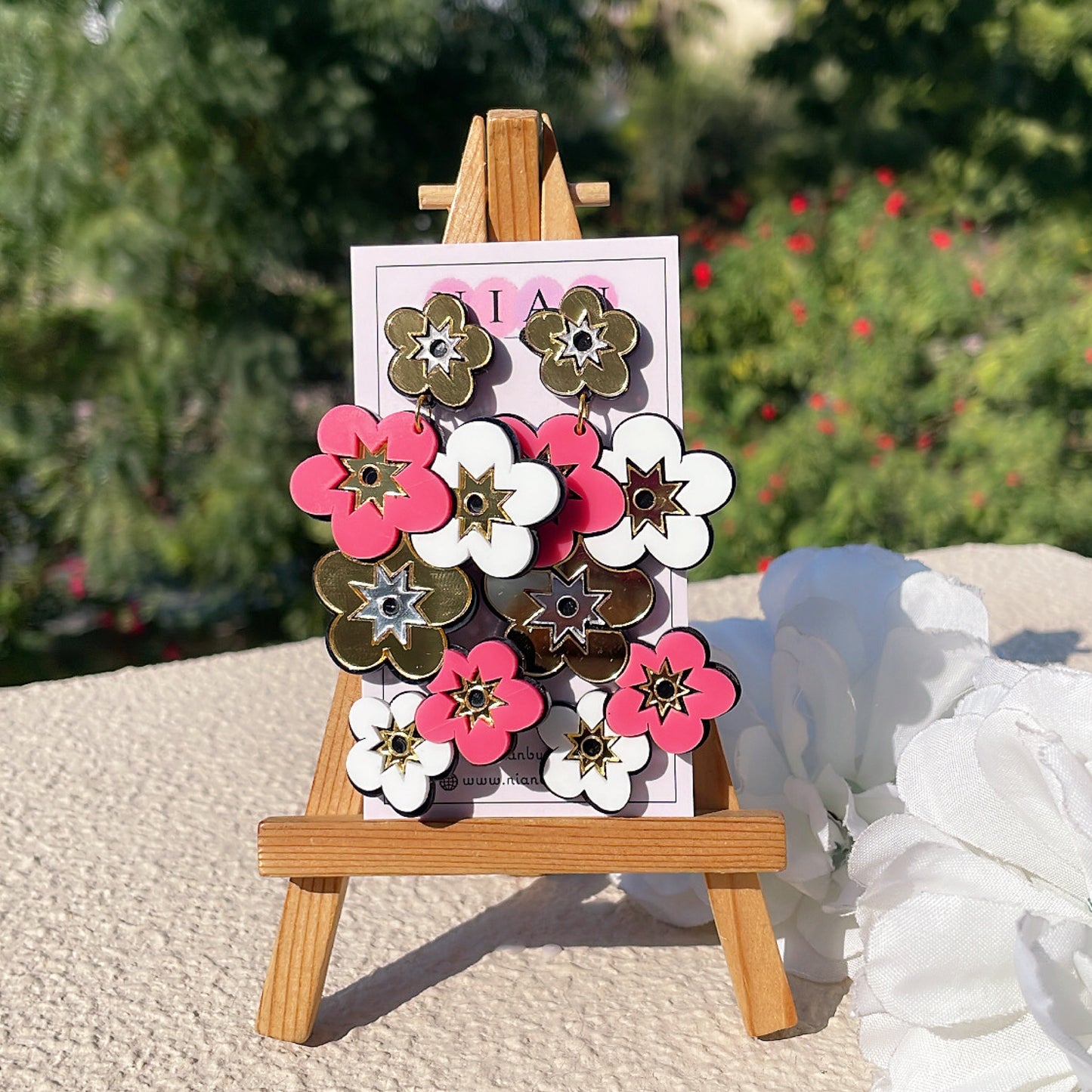 Floral Fetish Danglers - Glossy Golden, Pink and White - Nian by Nidhi - placed in a green and white background