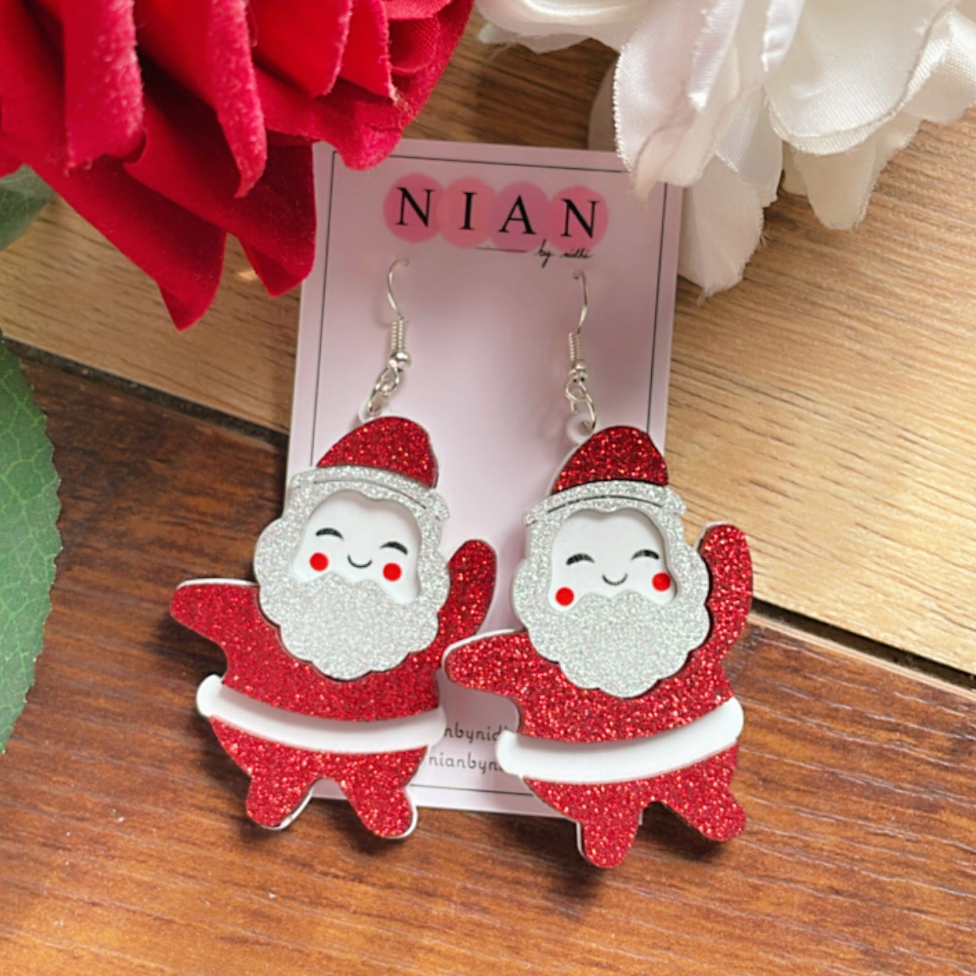 Dancing Santa Earrings - White and Shimmer Red- Nian by Nidhi - placed in a brown and flowery background
