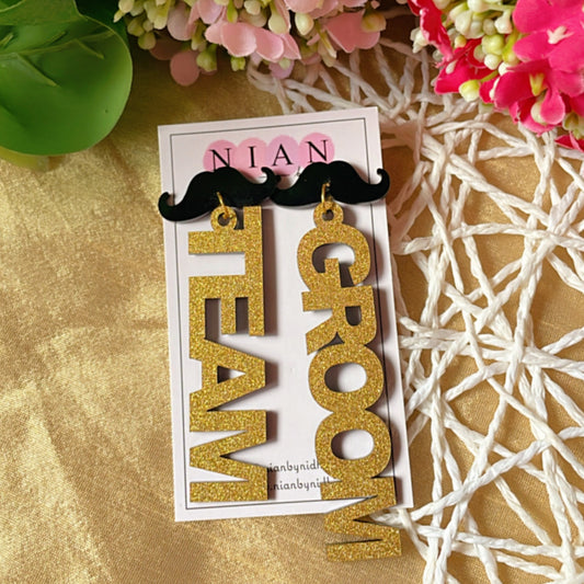 Team Groom Moustache Earrings - Shimmer Golden and Black - Nian by Nidhi - placed in a colorful background