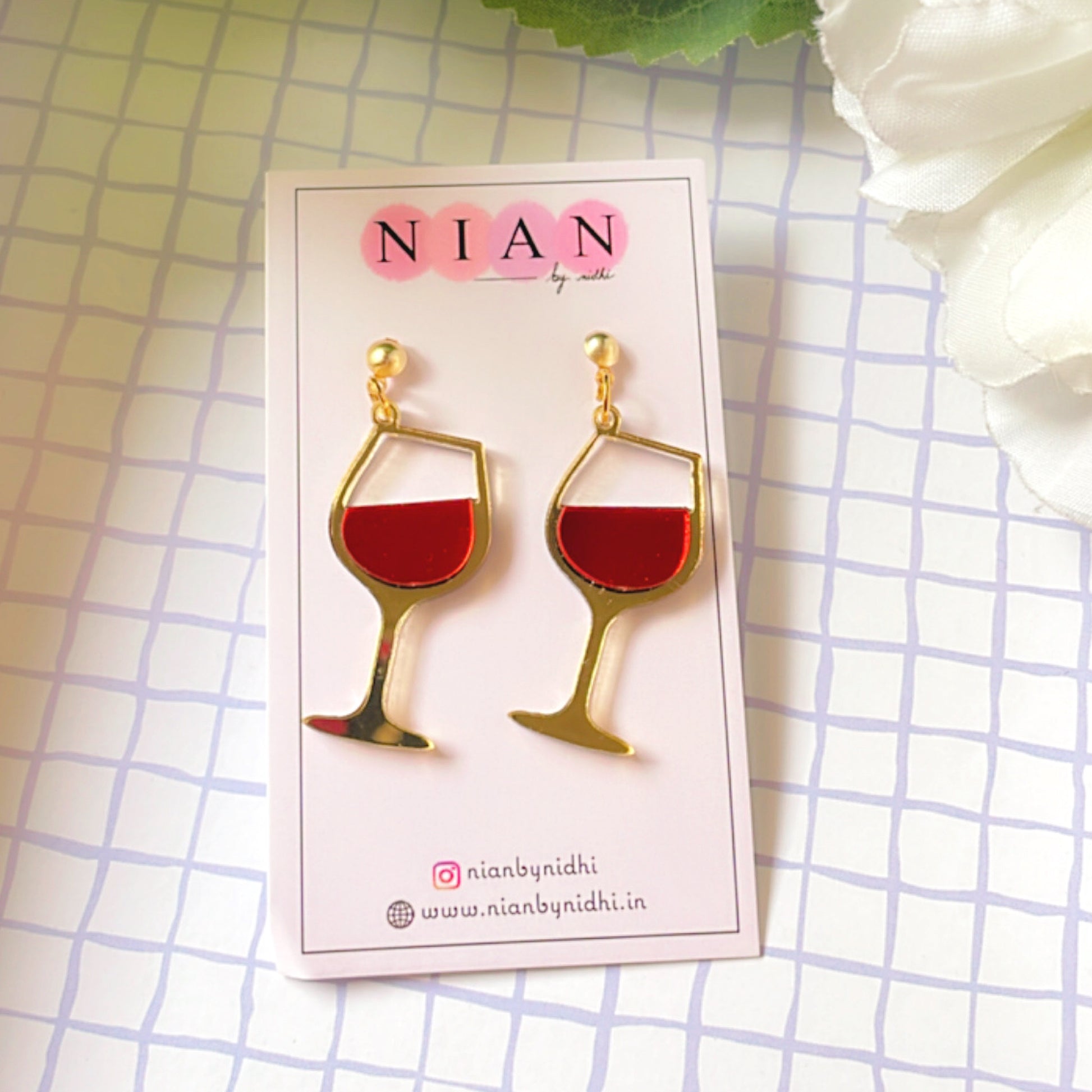 Wine Goblet Earrings - Glossy Red and Golden - Nian by Nidhi - placed in a squared-check background