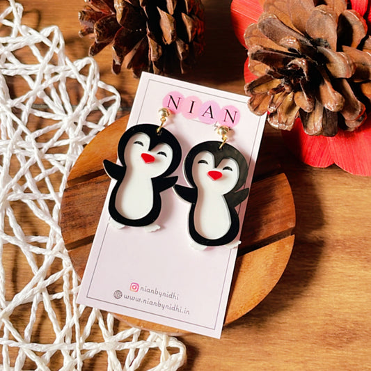 Punny Penguin Earrings - White, Black and Red - Nian by Nidhi - placed in a brown and white background