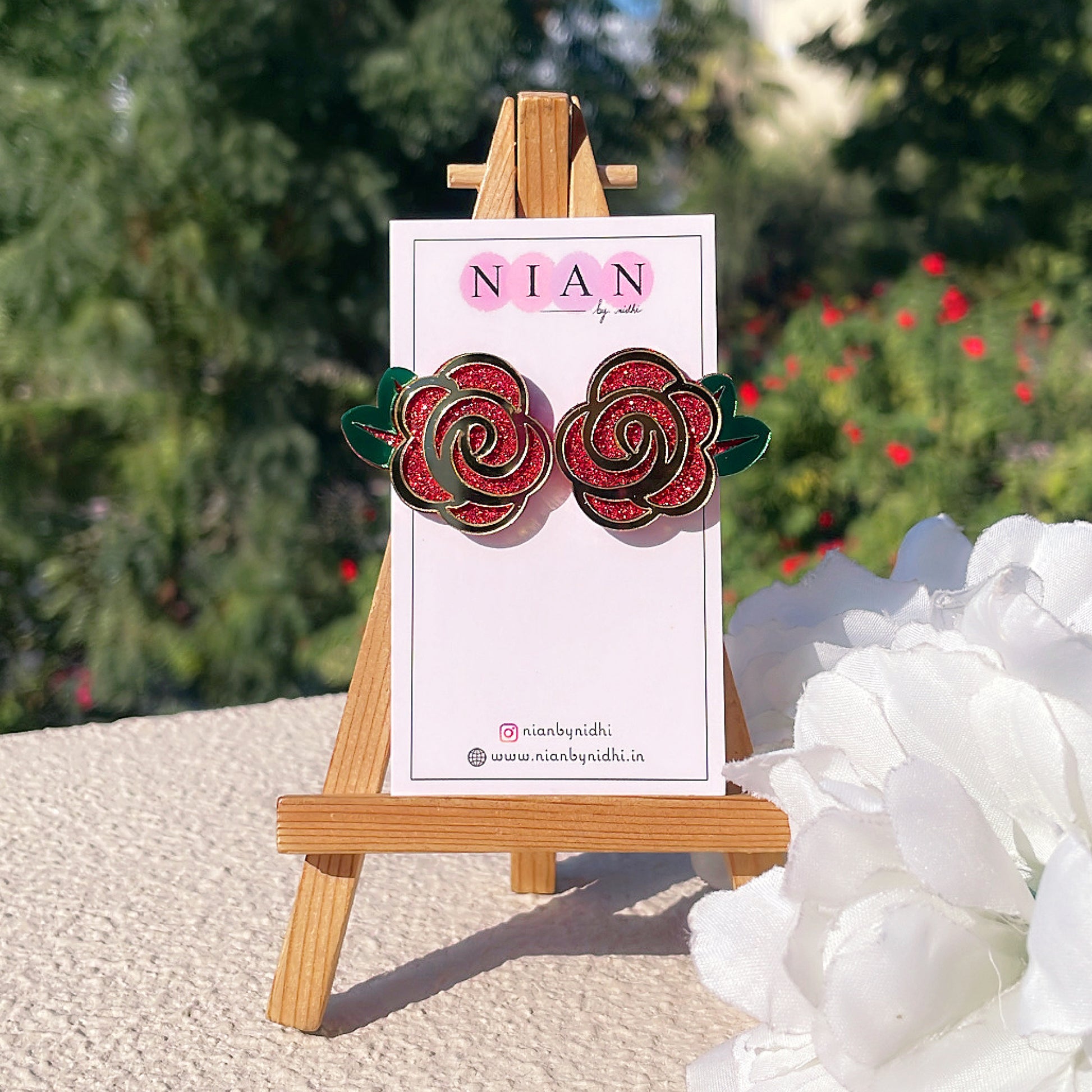 Ravishing Rose Earrings - Shimmer Red, Glossy Golden and Green - Nian by Nidhi - placed in a white and green background