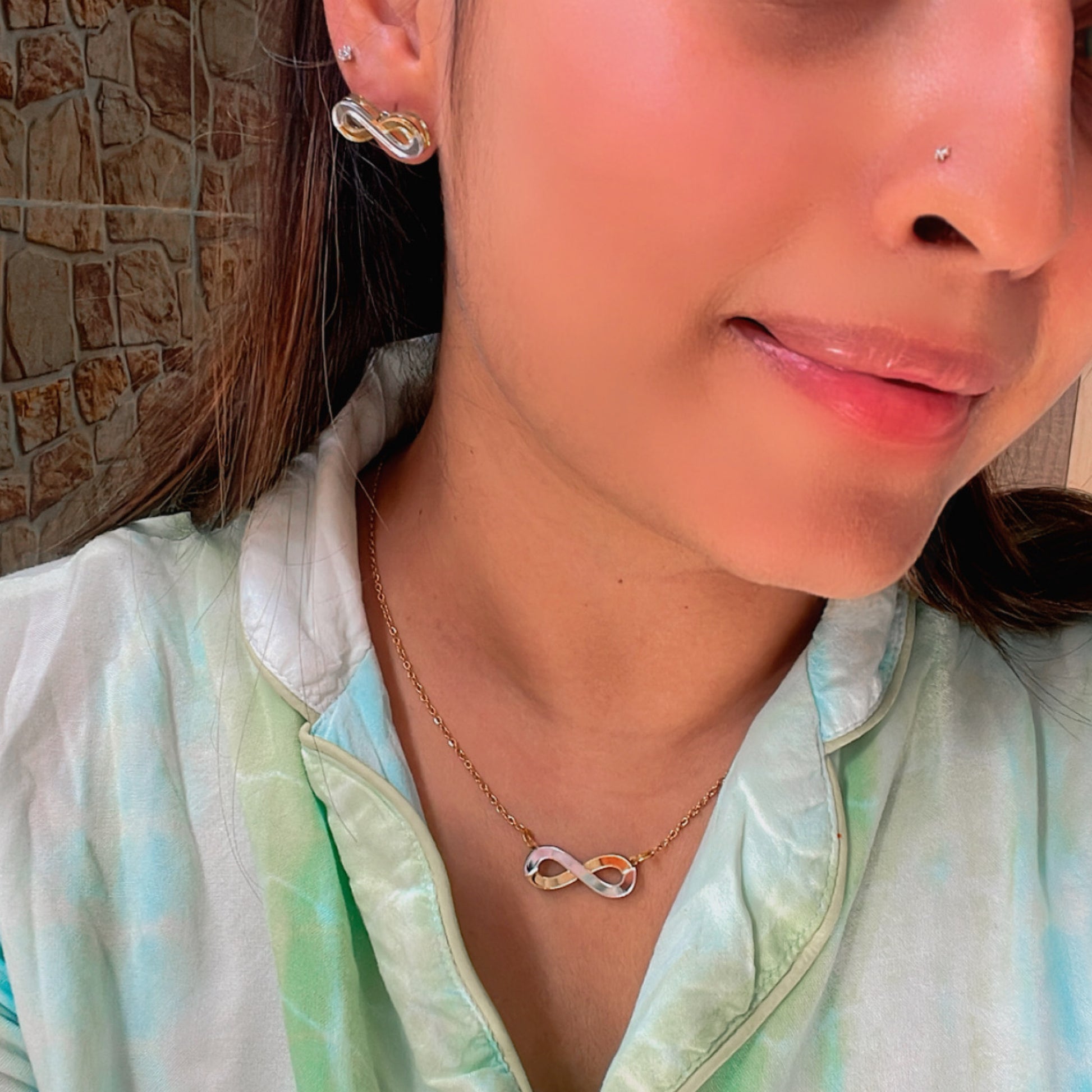 Infinity Combo (Set of 2) - Glossy Golden and Silver - Nian by Nidhi - comprises two products - Infinity Necklace and Infinity Studs - worn by a woman