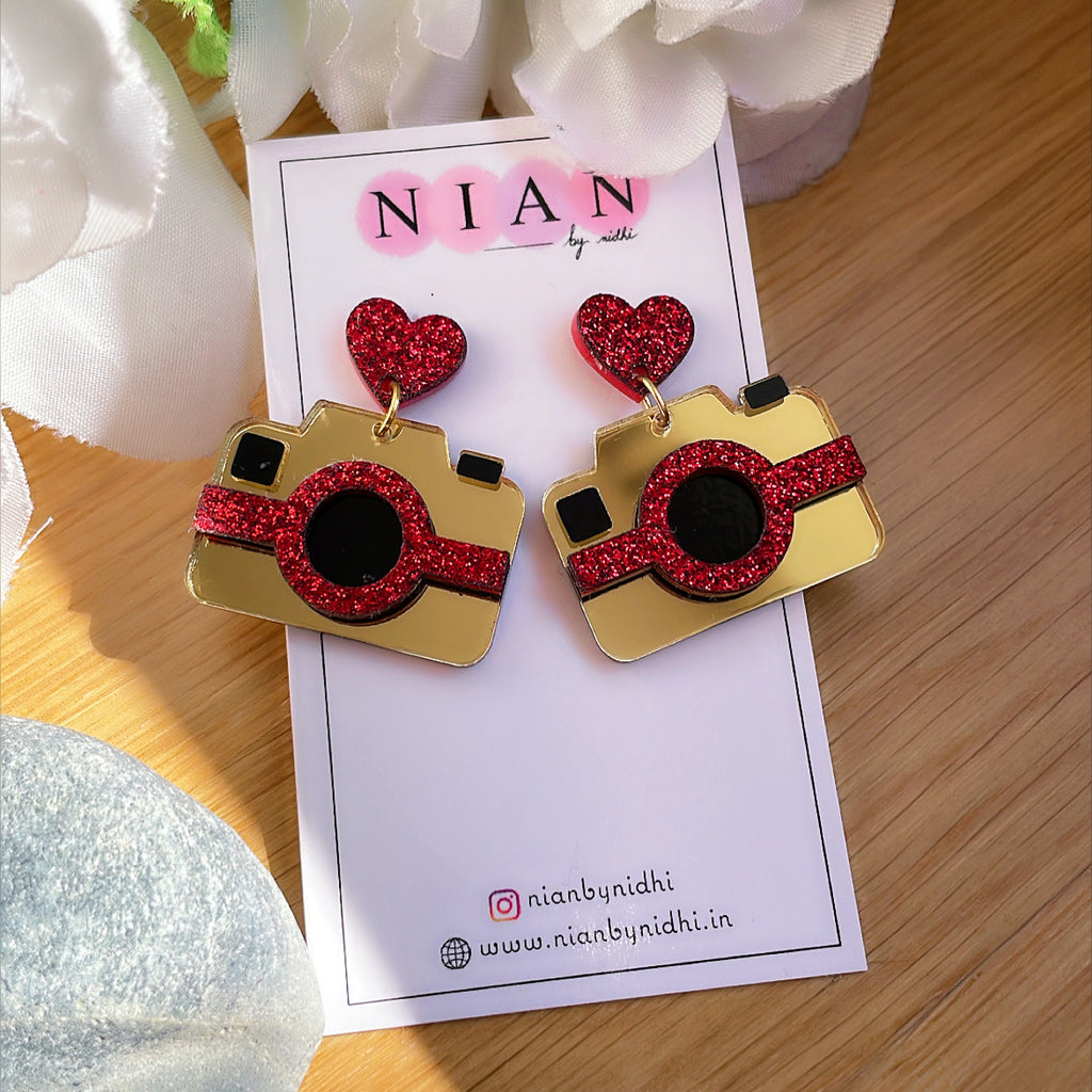 Camera Earrings - Multicolor - Glossy Golden and Shimmer Red - Nian by Nidhi - placed in a white and brown background