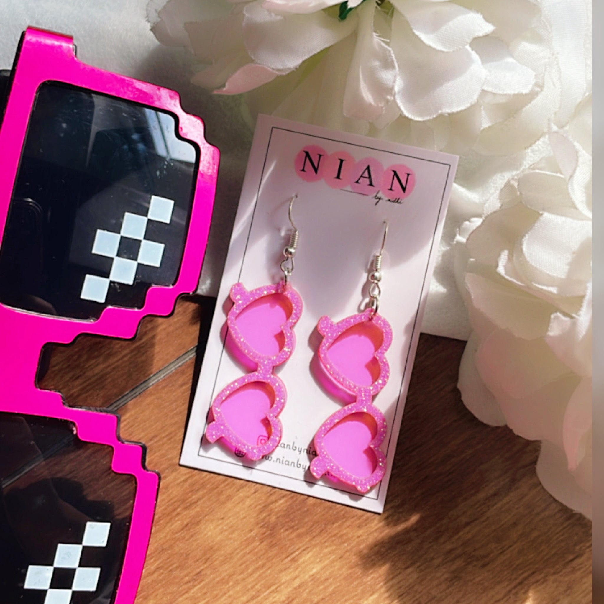 Glam Goggles Earrings - Shimmer Pink and Holographic Pink - Nian by Nidhi - placed in a white and brown background