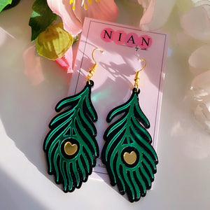 Morpankh Danglers - Glossy Green with Black and Golden details - Nian by Nidhi - placed in a white flowery background