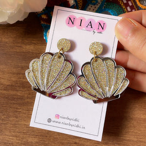 Shiny Shell Earrings - Nian by Nidhi - Shimmer Golden and Glassy Silver - placed in a brown and colorful background, held in a hand