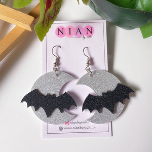 Spooky Night Earrings - Shimmer Silver and Shimmer Black - Nian by Nidhi - placed in a white and green background