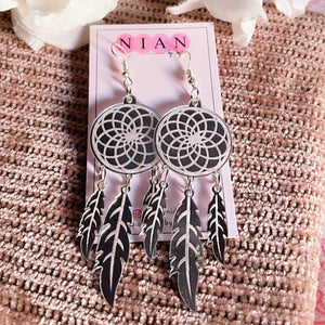 Dreamcatcher Earrings - Glossy Silver with embossing - Nian by Nidhi - placed in a light brown background