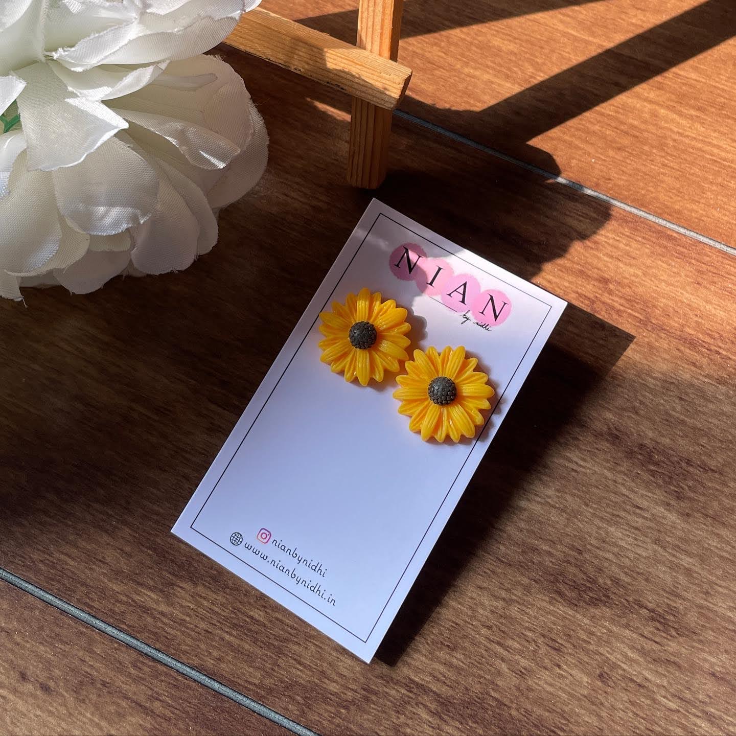 Sunkissed Sunflower Studs - Yellow - Nian by Nidhi - placed in a brown and white flowery background