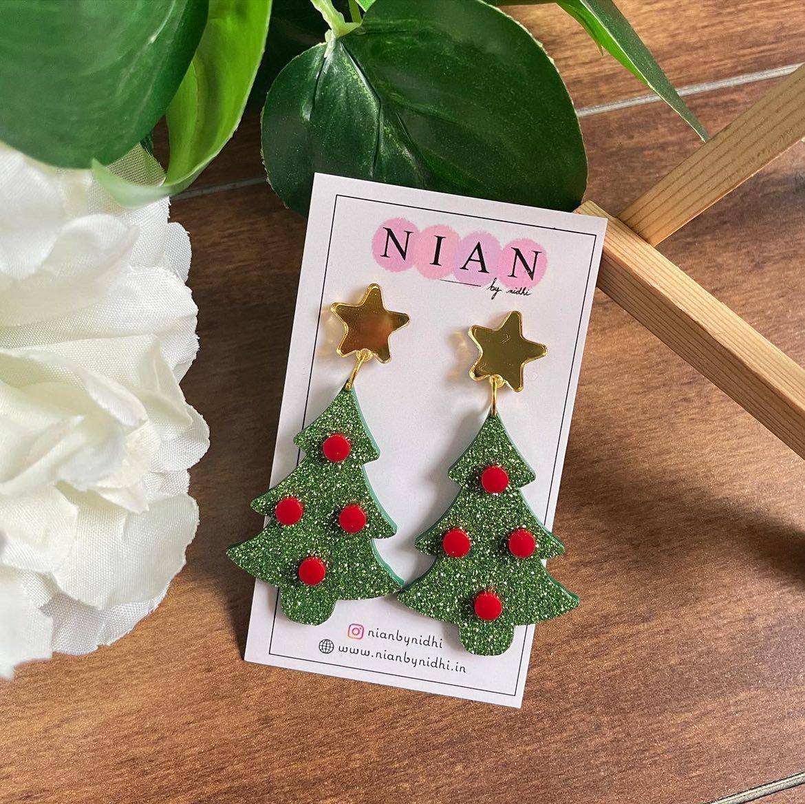 X-Mas Tree Earrings - Shimmer Green and Red - Nian by Nidhi - placed in a white and brown background, along with a Nian by Nidhi Earring Card