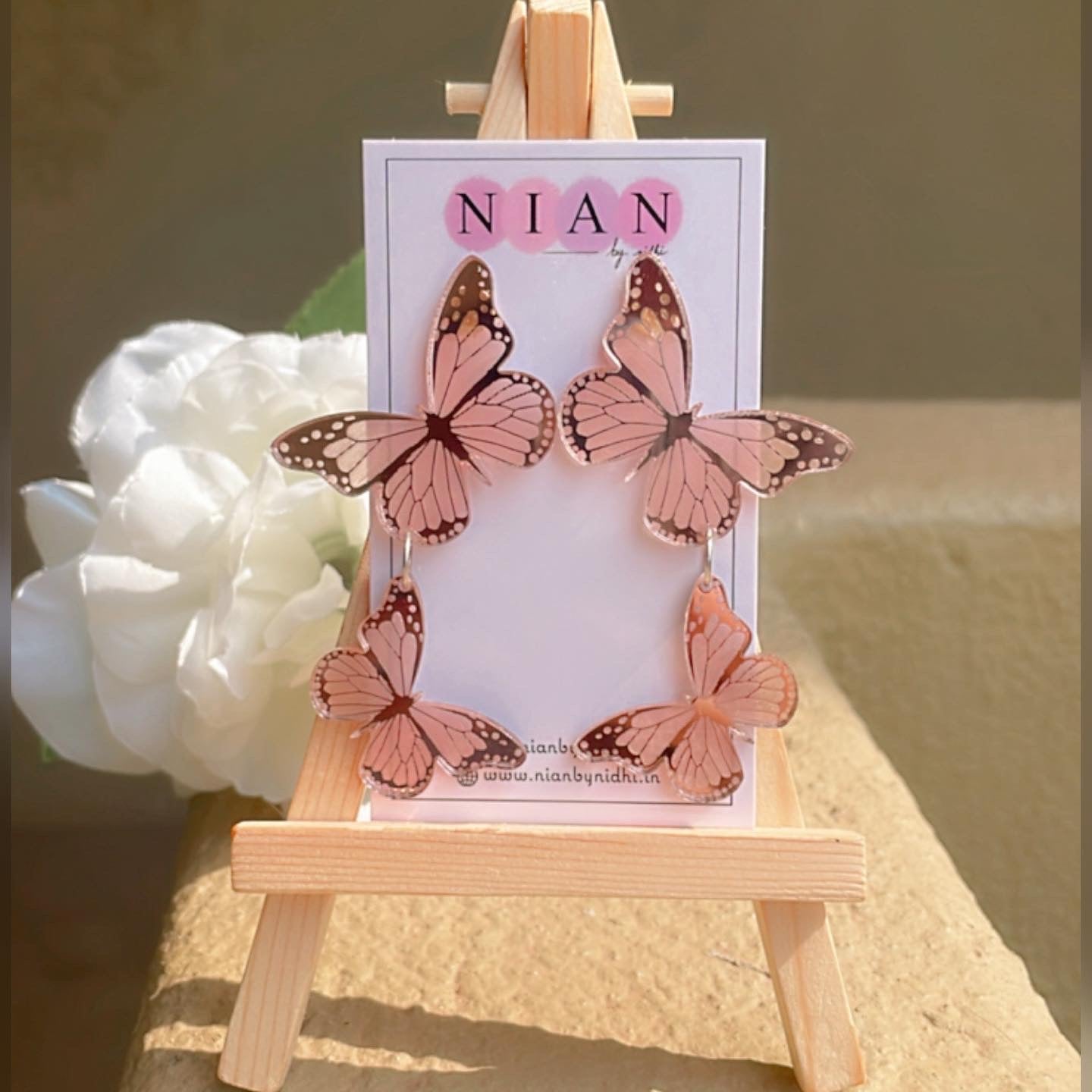 Butterfly Earrings - Glossy Rosegold - Nian by Nidhi - placed on a small wooden canvas
