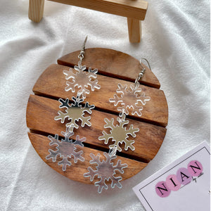 Snowflake Danglers - holographic, glassy blue, and silver - Nian by Nidhi - placed in a white background with a Nian by Nidhi Earring card