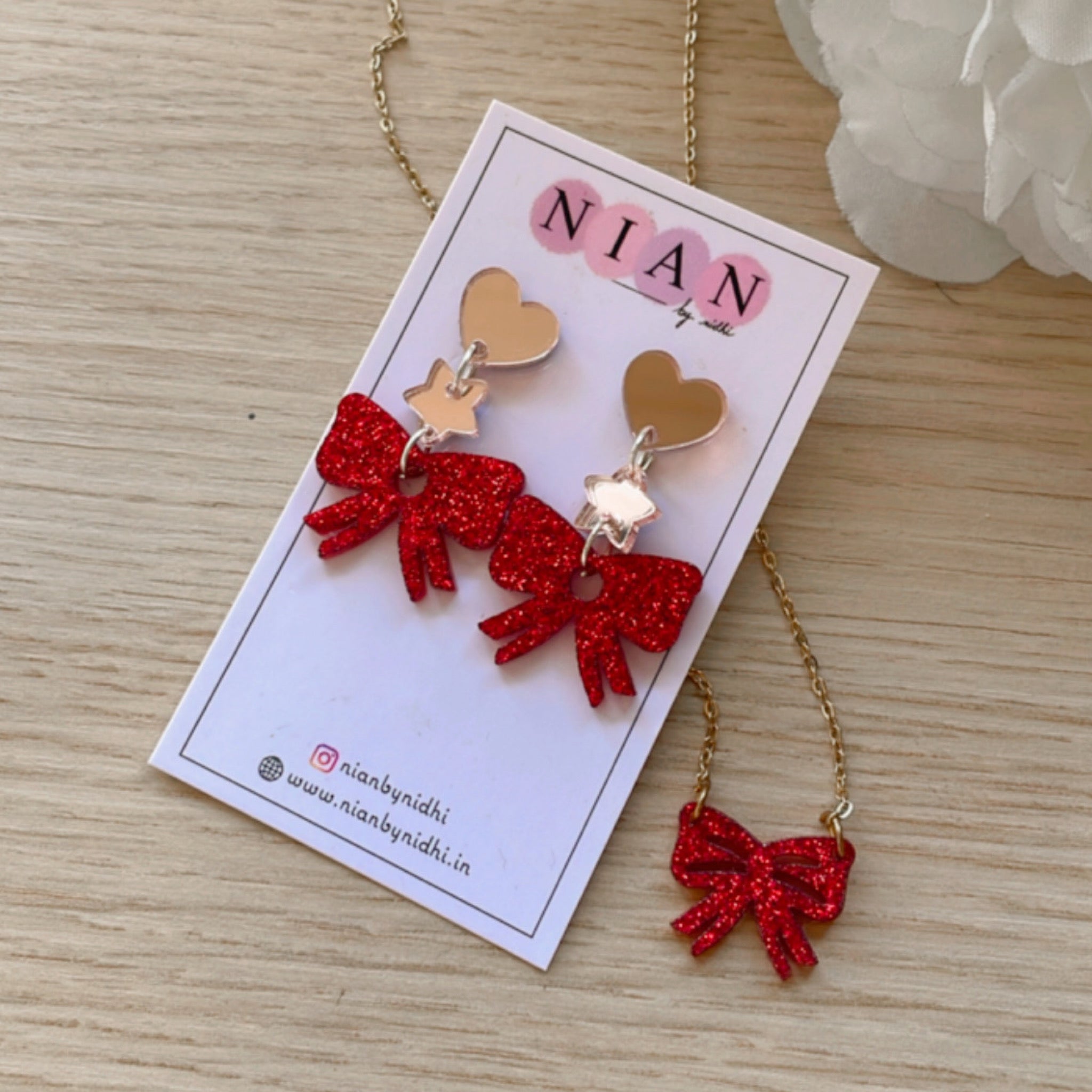Bow Danglers & Bow Necklace - Shimmer Red - Nian by Nidhi - placed in a brown background