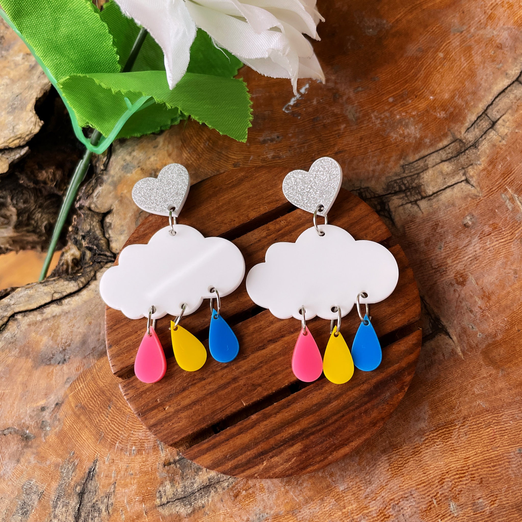 Rainy Cloud Earrings - multi color - Pink, Yellow, and Blue, with white clouds and silver hearts - Nian by Nidhi - in a white, green, and brown background