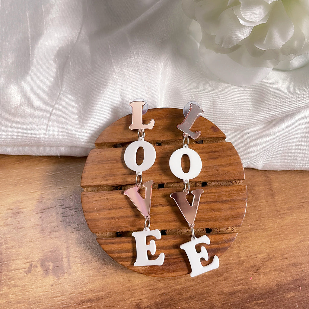 Rosegold Love Earrings - Rosegold and white colors - contains acrylic based four letters of "LOVE" - Nian by Nidhi - in a white and brown background