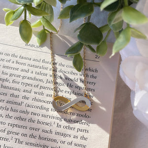 Infinity Necklace - Glossy Golden and Silver - Nian by Nidhi - placed in a white and green background, placed on a book