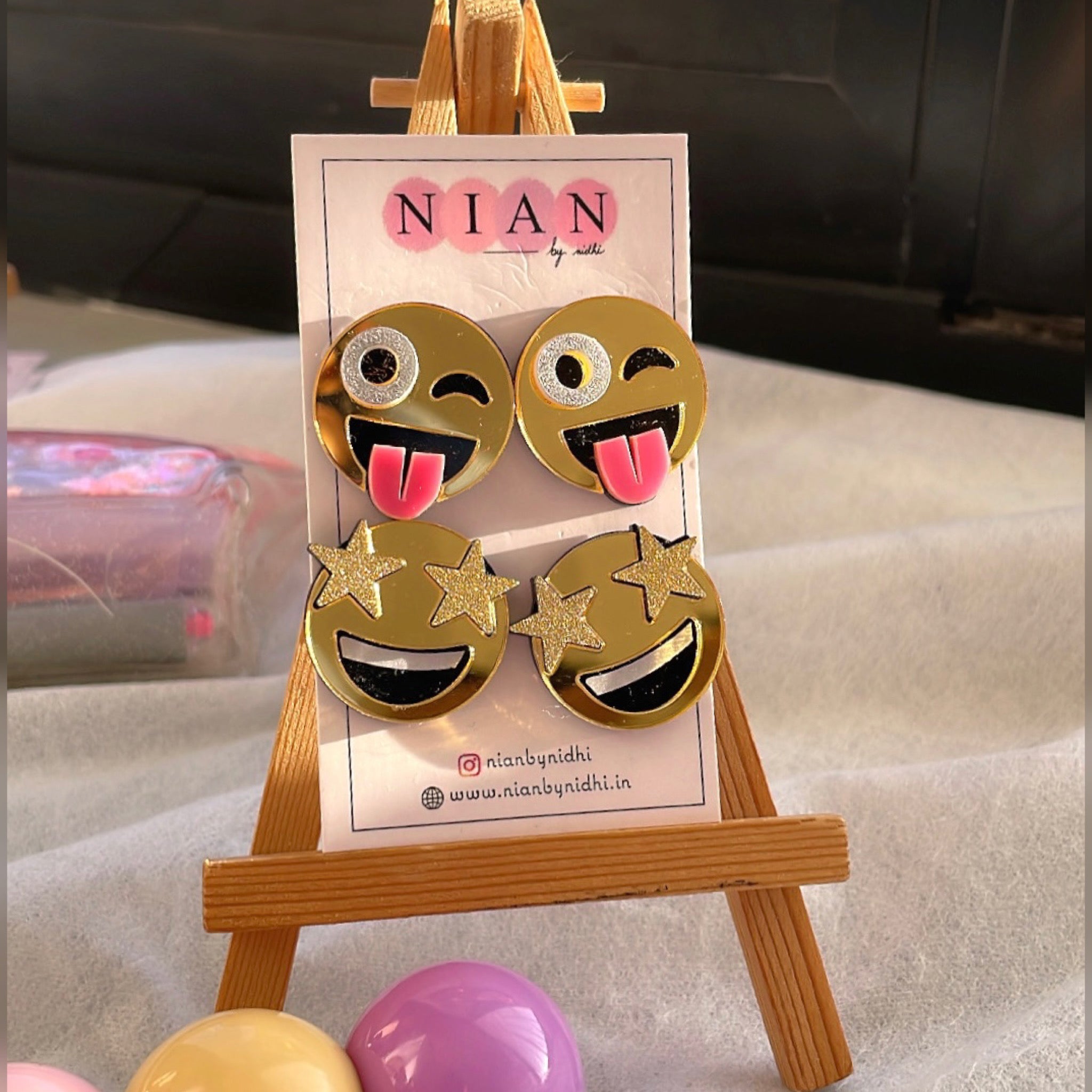 Emoji Studs Combo (Set of 2) - consists Goofy Emoji Studs and Star-Struck Emoji Studs - Golden with face detailings - Nian by Nidhi - placed on a small wooden canvas