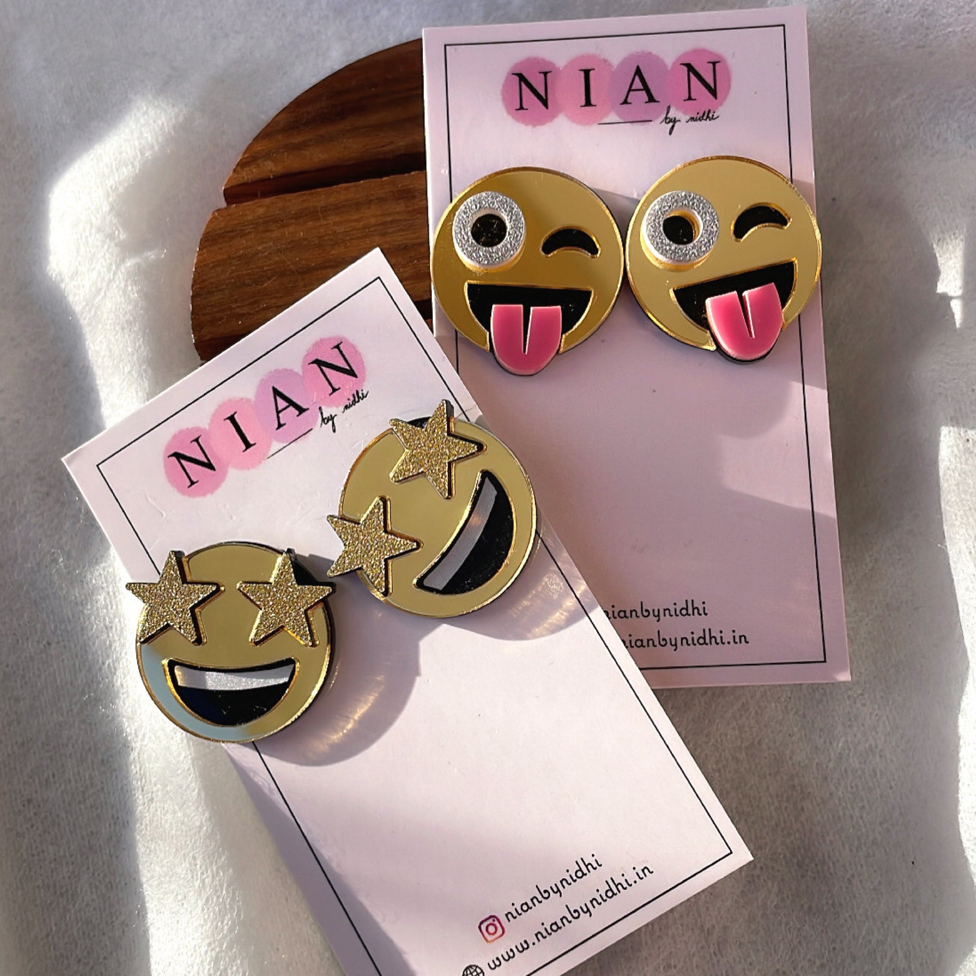 Emoji Studs Combo (Set of 2) - consists Goofy Emoji Studs and Star-Struck Emoji Studs - Golden with face detailings - Nian by Nidhi - placed in a white and brown background