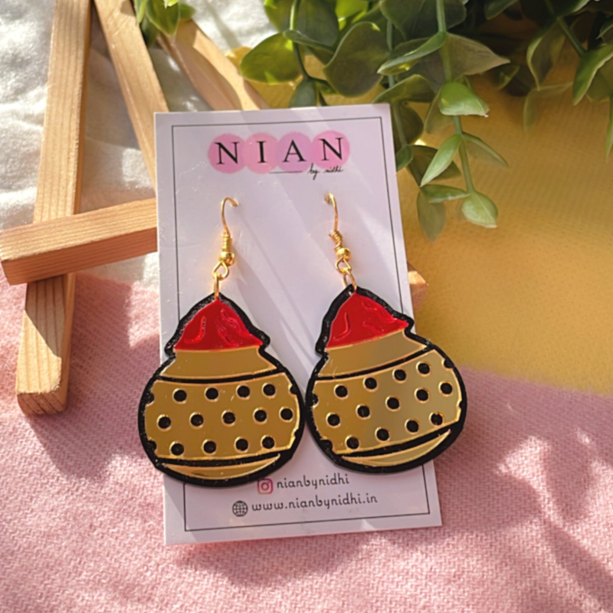 Gulal ki Matki Earrings - Glossy Golden and Red - Nian by Nidhi - placed in a colorful background