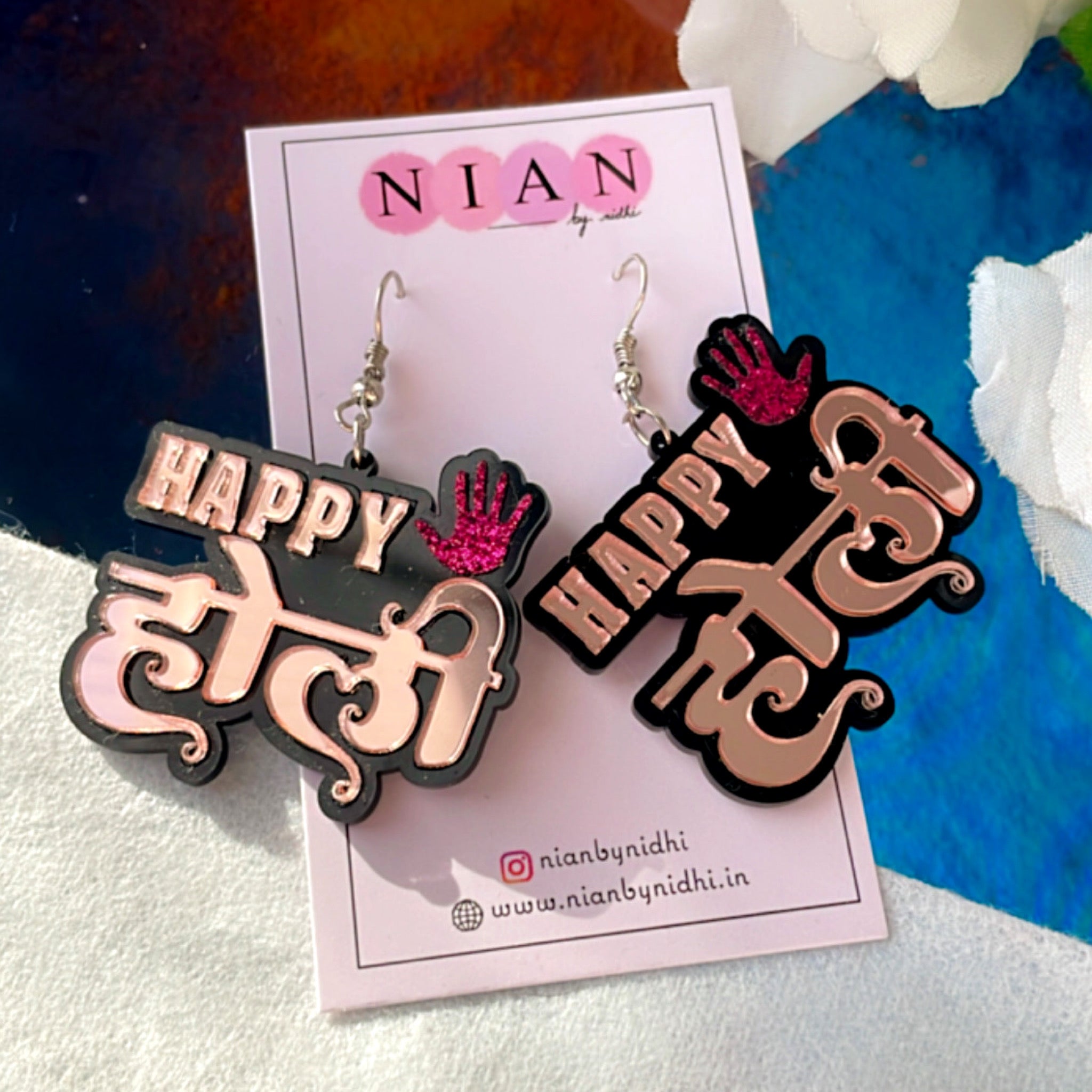 Happy Holi Earrings - Rosegold and Shimmer Pink - Nian by Nidhi - placed in a colorful background