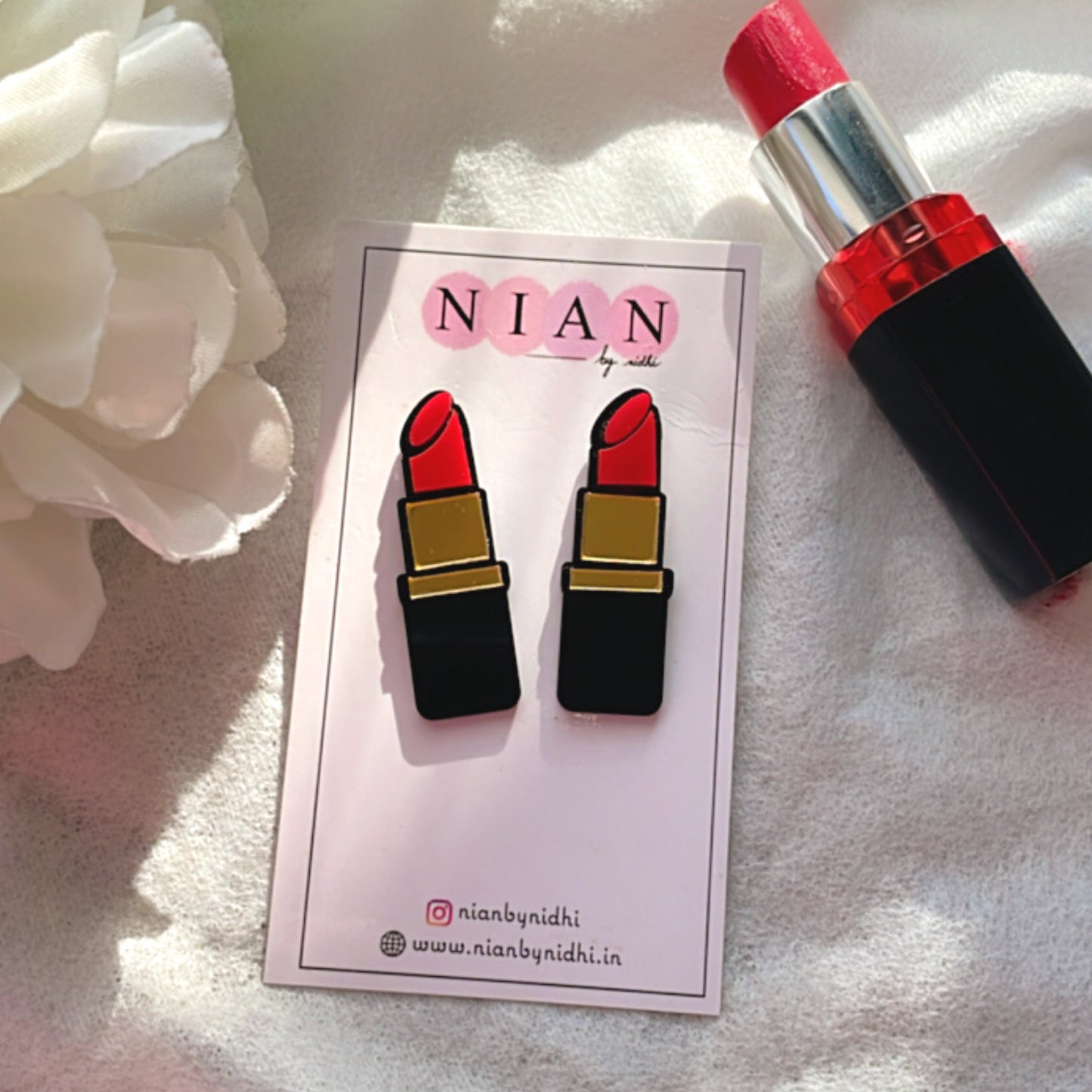 Lipstick Studs - Black and Red - Nian by Nidhi - placed in a white background, along with an actual lipstick