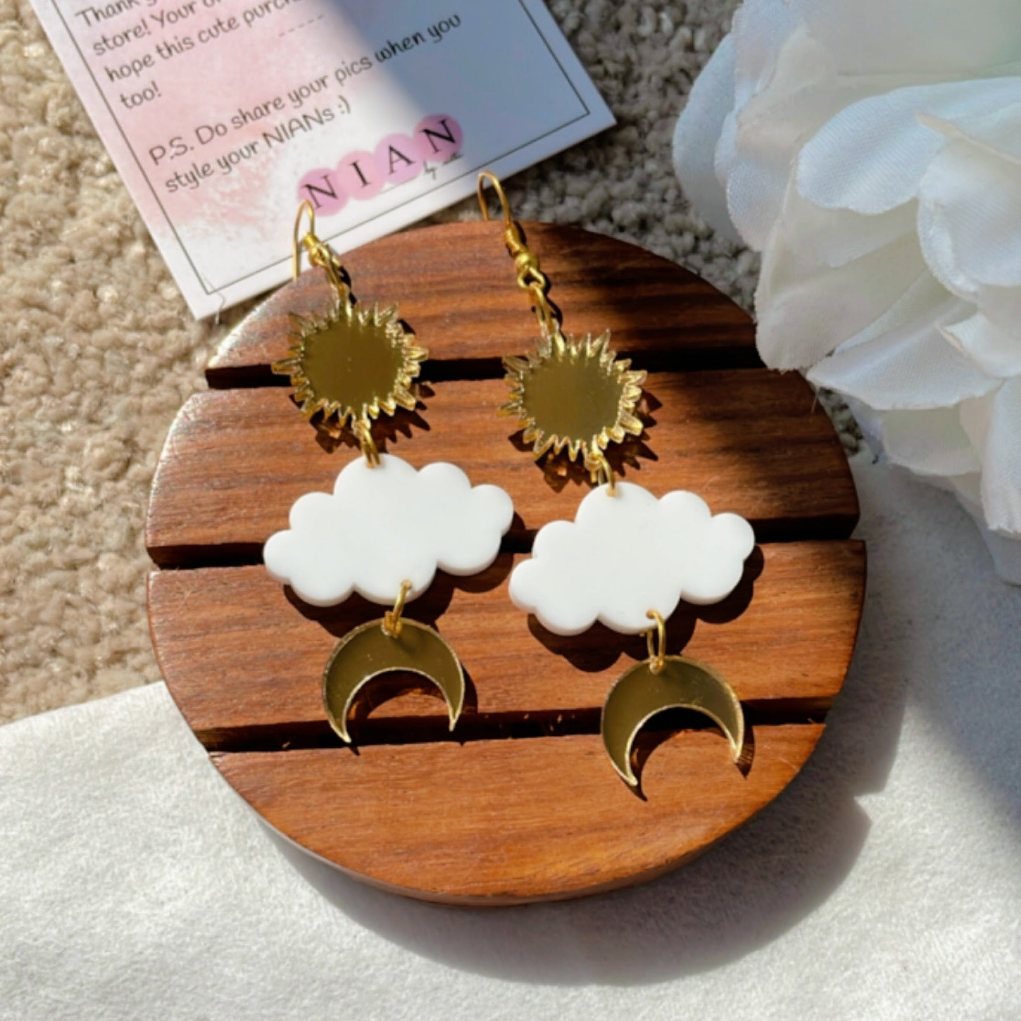 Shining Sky Danglers - Glossy Gold and White - Nian by Nidhi - placed in a white and beige background
