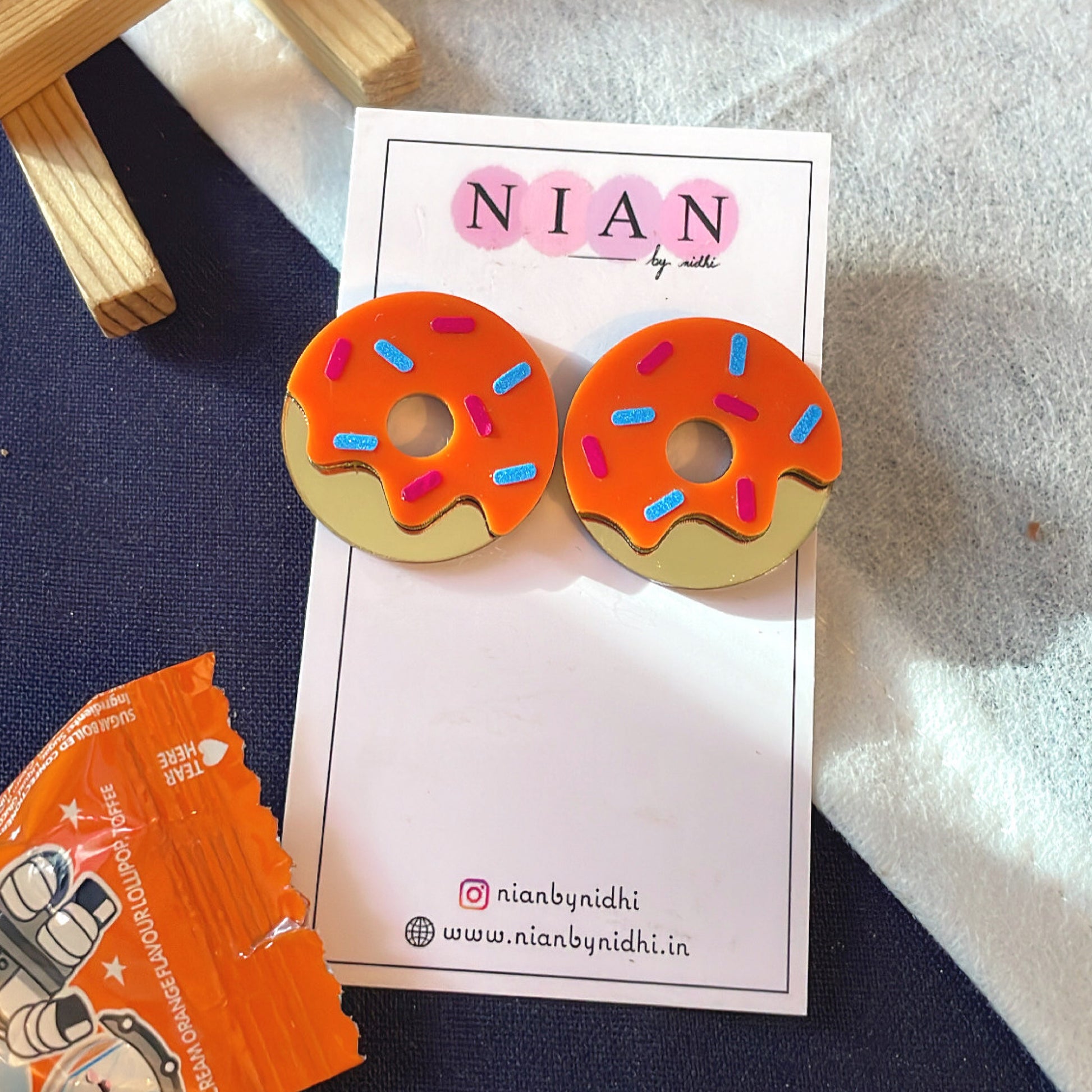 Donut Delight Earrings - Orange and Golden - Nian by Nidhi - placed in a white and blue background