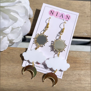 Shining Sky Danglers - Glossy Gold and White - Nian by Nidhi - placed in a white and beige background