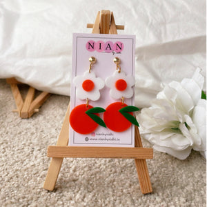 Orange Blossom Earrings - Orange and White - Nian by Nidhi - placed in a white and light beige background, on a small wooden canvas