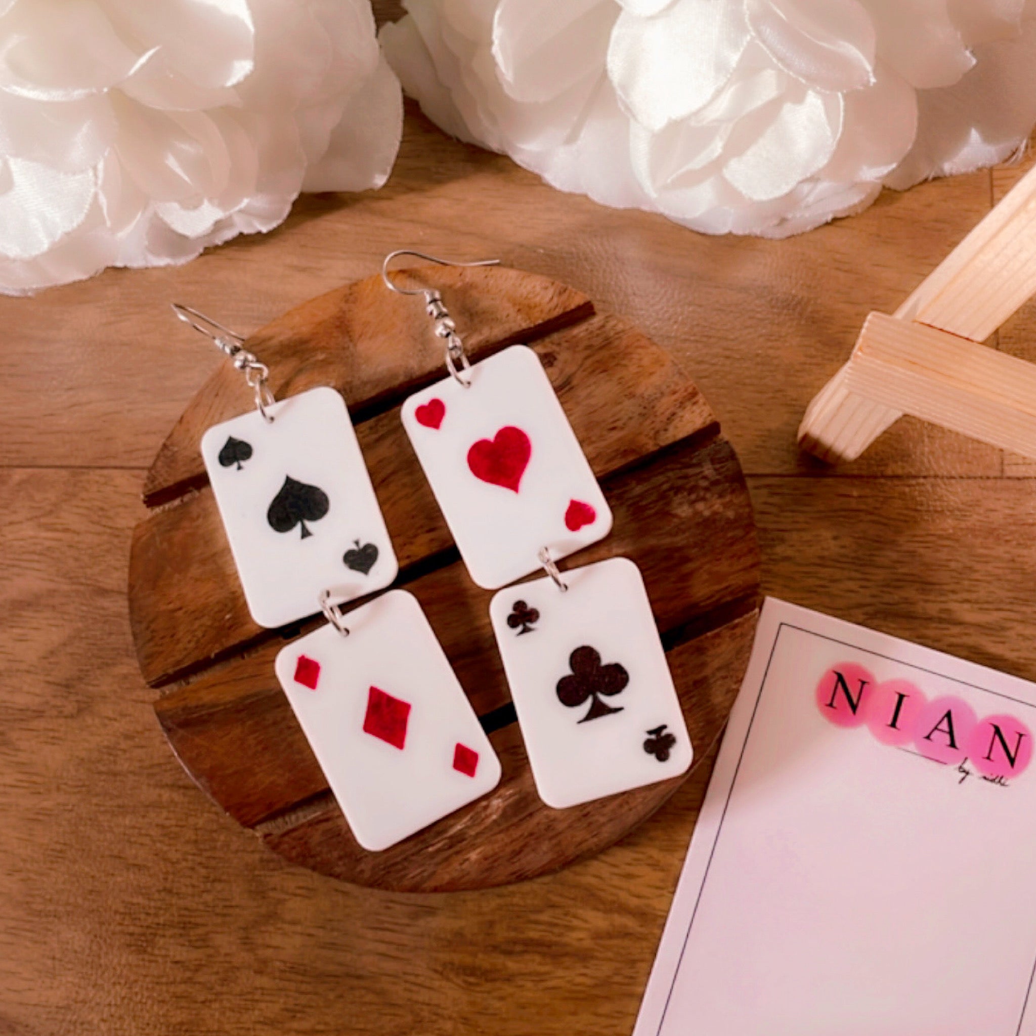 Poker Earrings - White - Nian by Nidhi - placed in a brown and white flower background