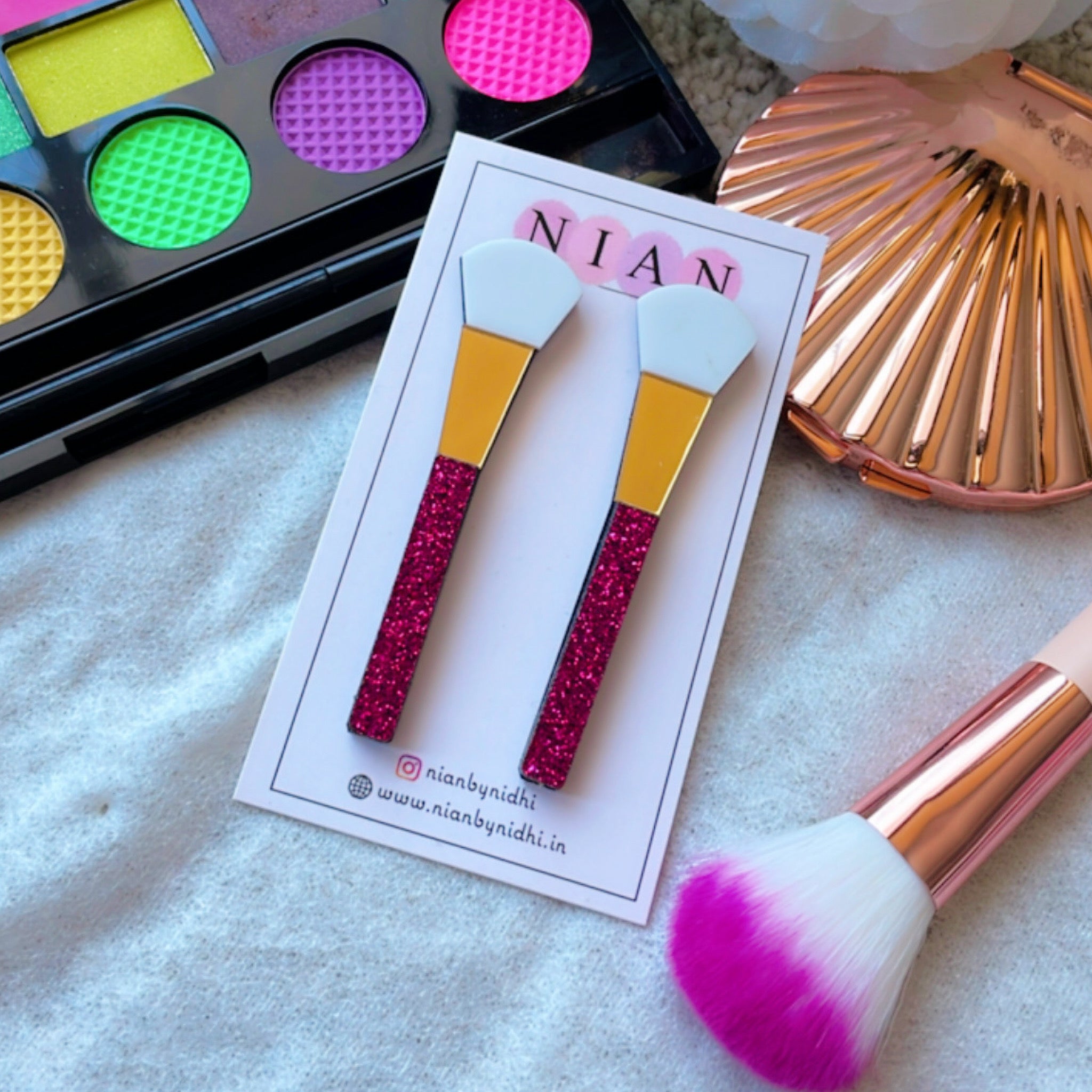 Makeup Brush Earrings - white, golden and glitter pink - Nian by Nidhi - placed in a white background with actual makeup things