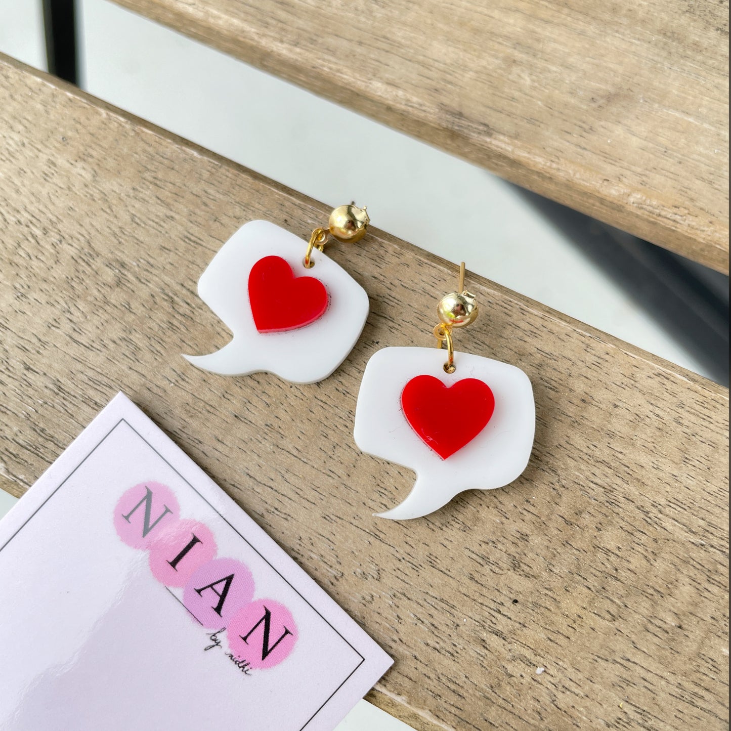 Message from Heart Earrings - Nian by Nidhi - White and Red - placed in a light brown background