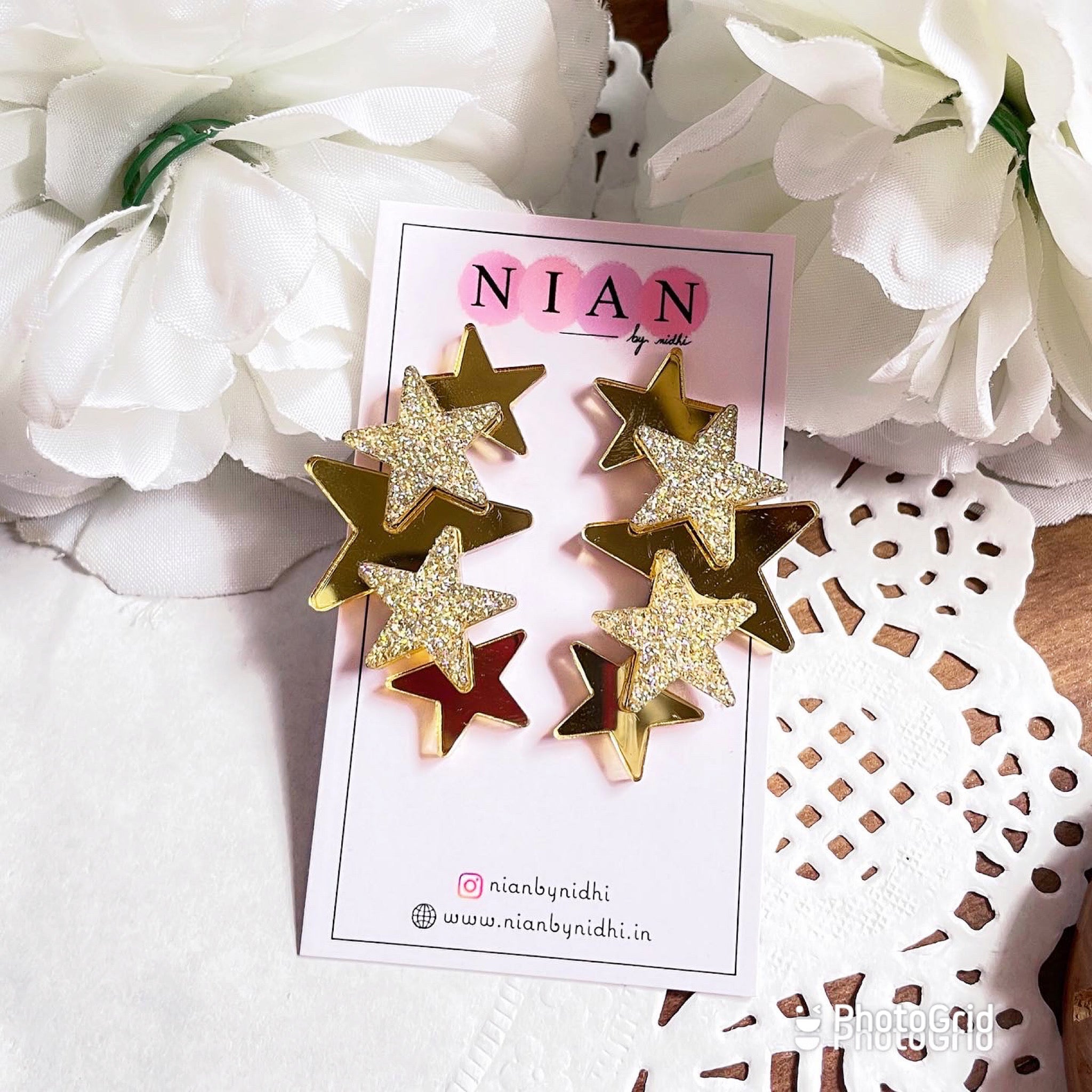 Glitter Star Earrings - Nian by Nidhi - Golden and Glitter Golden - placed in a white flowery background