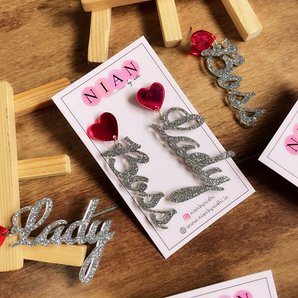 Boss Lady Earrings - Nian by Nidhi - Glossy Pink and Glitter Silver - placed in a brown wooden background